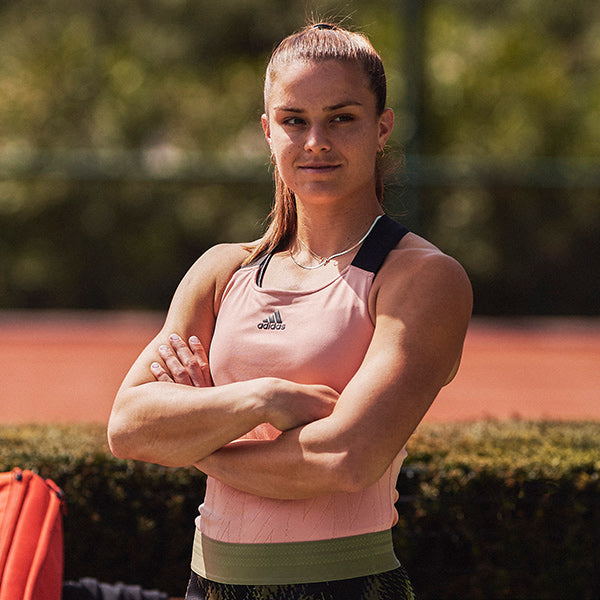 Woman posing with arms crosed wearing pink and black women's adidas tennis clothing