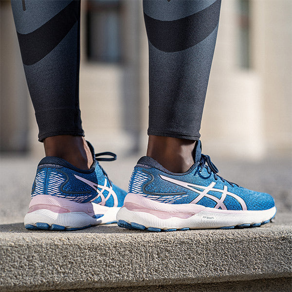 Woman standing on a sidewalk in blue and pink ASICS running shoes