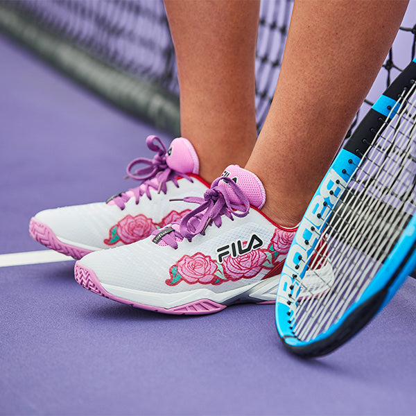 Close up of woman wearing pink, white and red Fila tennis shoes on court