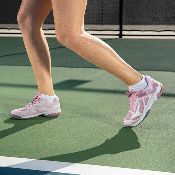 Woman on tennis court wearing pink and white Women's Mizuno Tennis Shoes