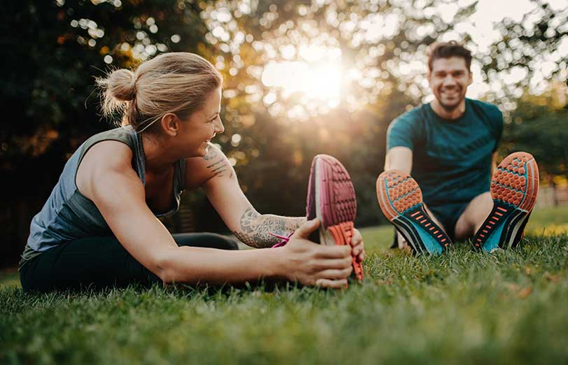 Smiling woman and man stretching in park