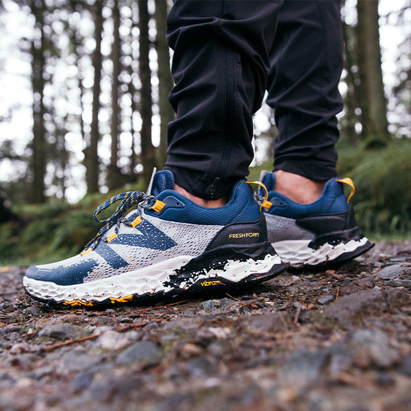 Man standing in woods wearing New Balance Men's Trail Running Shoes