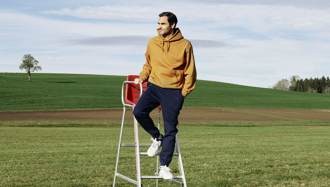 Roger Federer in grassy field in the On The Roger Federer Advantage tennis shoes