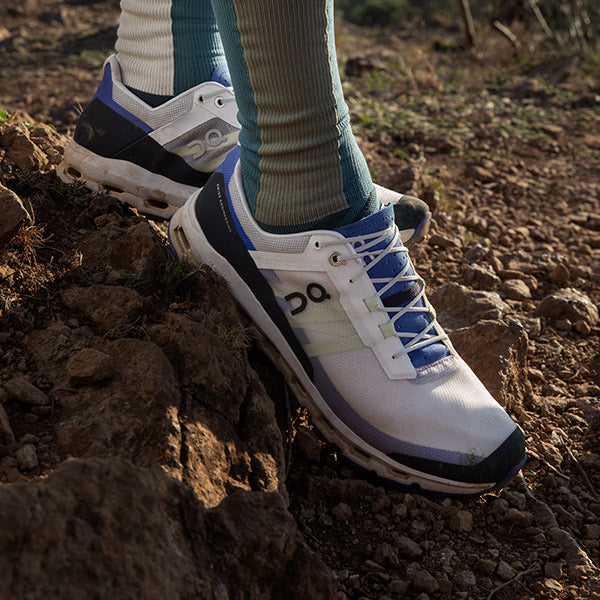 Close up of On Cloudvista Men's Frost/Ink trail running shoes on rocky trail.