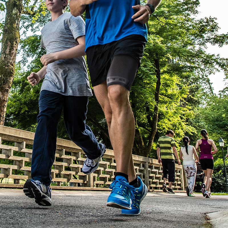 Man running in park with OS1ST compression leg sleeve