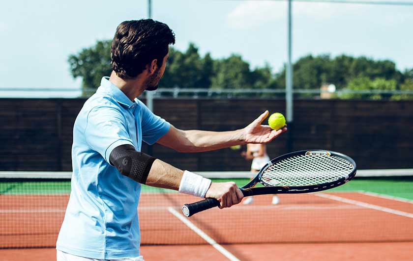 Man playing tennis in OS1ST elbow compression sleeve