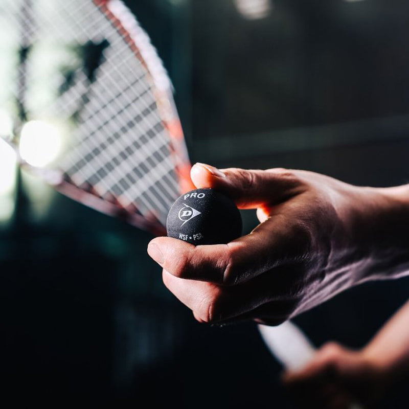 Close-up of man holding black squash ball