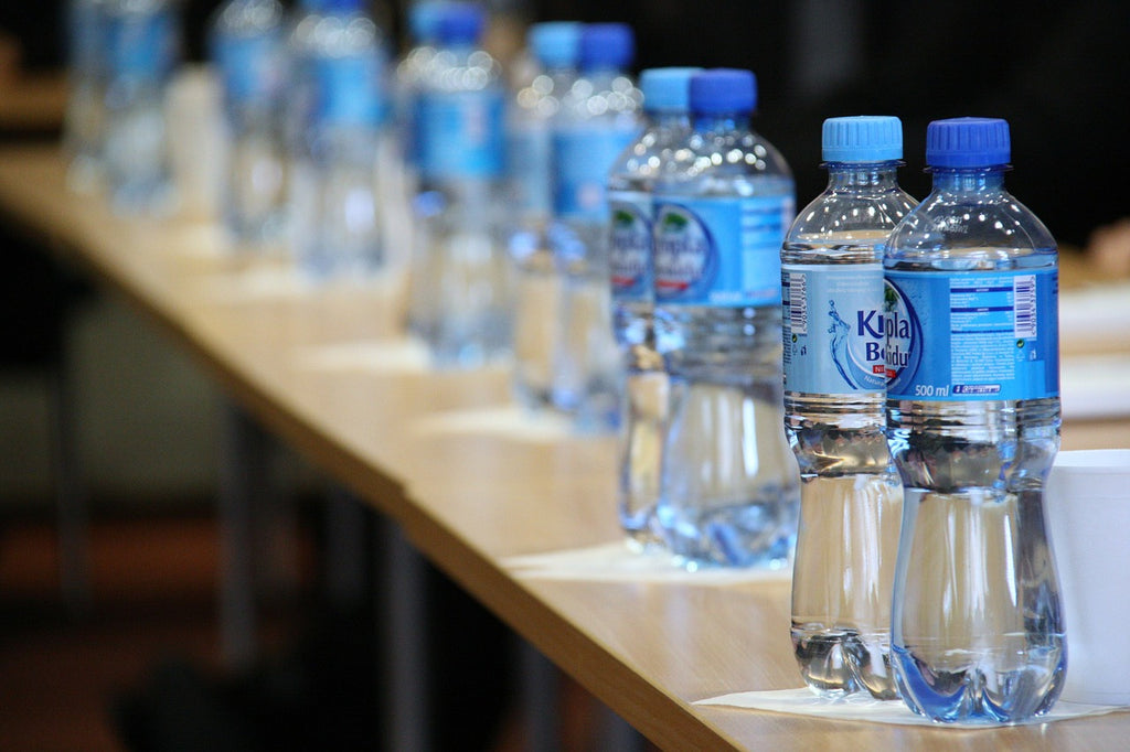 Long row of plastic water bottles on wooden table
