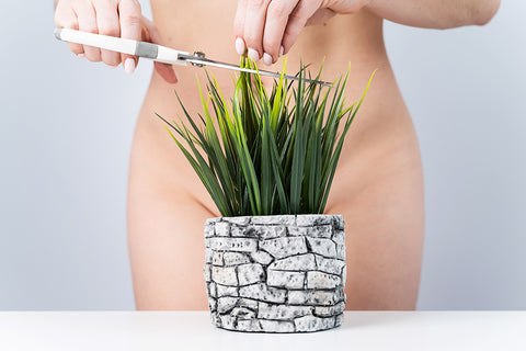 Woman cutting a plant as it covers her bikini area