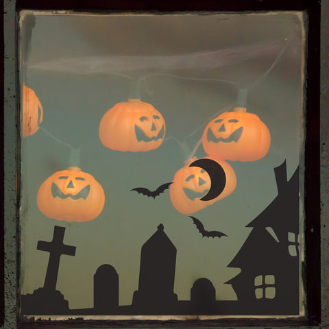 Spooky village window sticker with floating pumpkins behind it