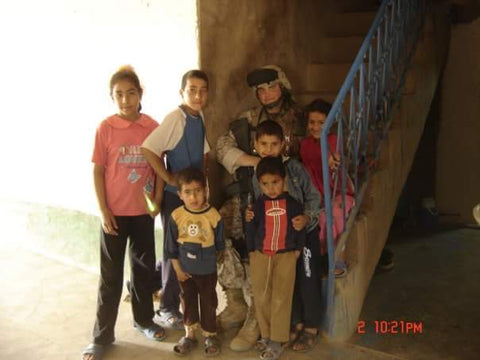 LCpl. Brett Wightman with children in Iraq