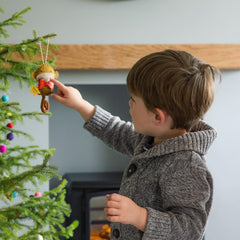 Child decorating a Christmas tree with a personalised monkey ornament