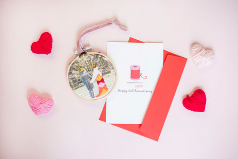 a flatlay image of a 2nd year anniversary card with a cotton wheel on it, and an embroidered photo hoop next to it.