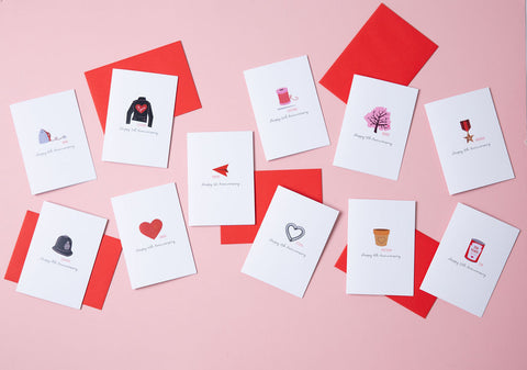 A selection of anniversary cards for each year of an anniversary based on the traditional gifts for that year. The cards are white and come with a red envelope.