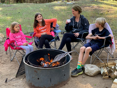 Kids and their family sitting around a fire drinking from HaloVino sustainable glasses.