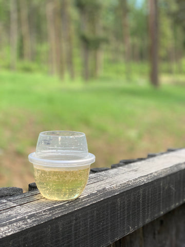 A HaloVino sustainable glass filled with wine resting on a fence.