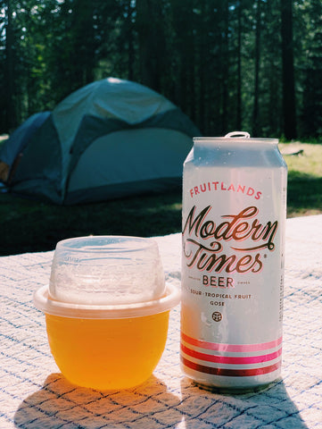 A HaloVino sustainable glass filled with beer next to the beer can.