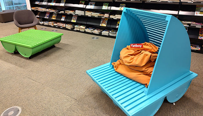 Young readers immersed in books, seated on Fatboy's beanbags at BAnQ's serene reading space.