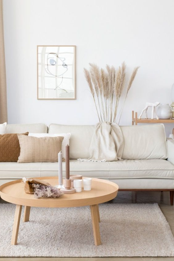 Living room with couch, area rug pillows in neutral tones and a round wood coffee table