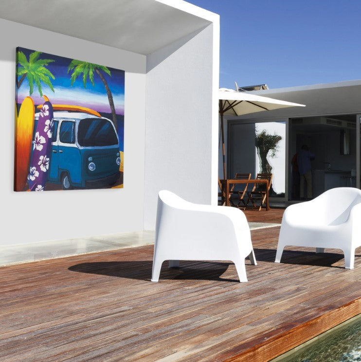 Surf Mini Bus Outdoor Canvas Art Print hanging on a white wall with white chairs on a wood platform.  