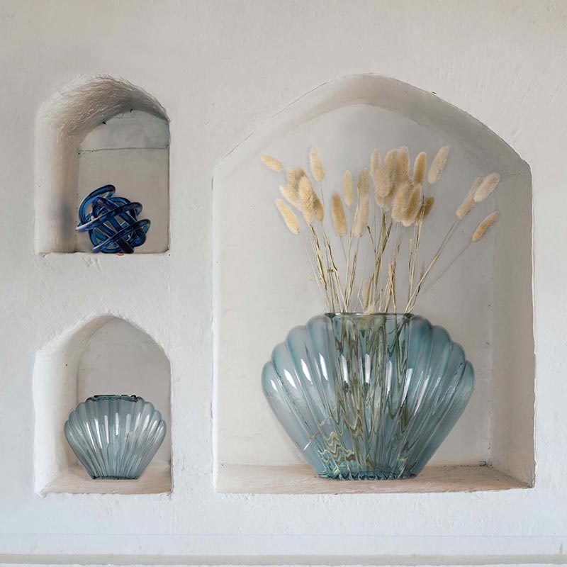 Amreican Art Decor's Sea Scallops Azure Glass Vase Set and as the tides turn table top knots in blue placed in arched wall shelving.