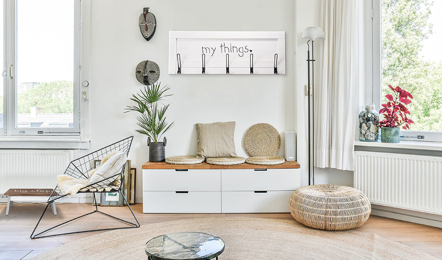 White room with 2 windows, chest of drawers, chairs, stepstool and wall coat hanger.