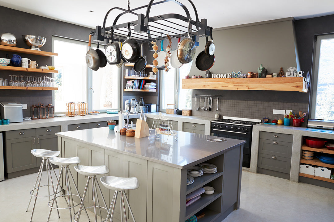 Kitchen with center island with stools, hanging pots and pans, floating shelves, oven and cabinets