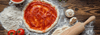 Pizza dough with sauce on it sitting on a floured table