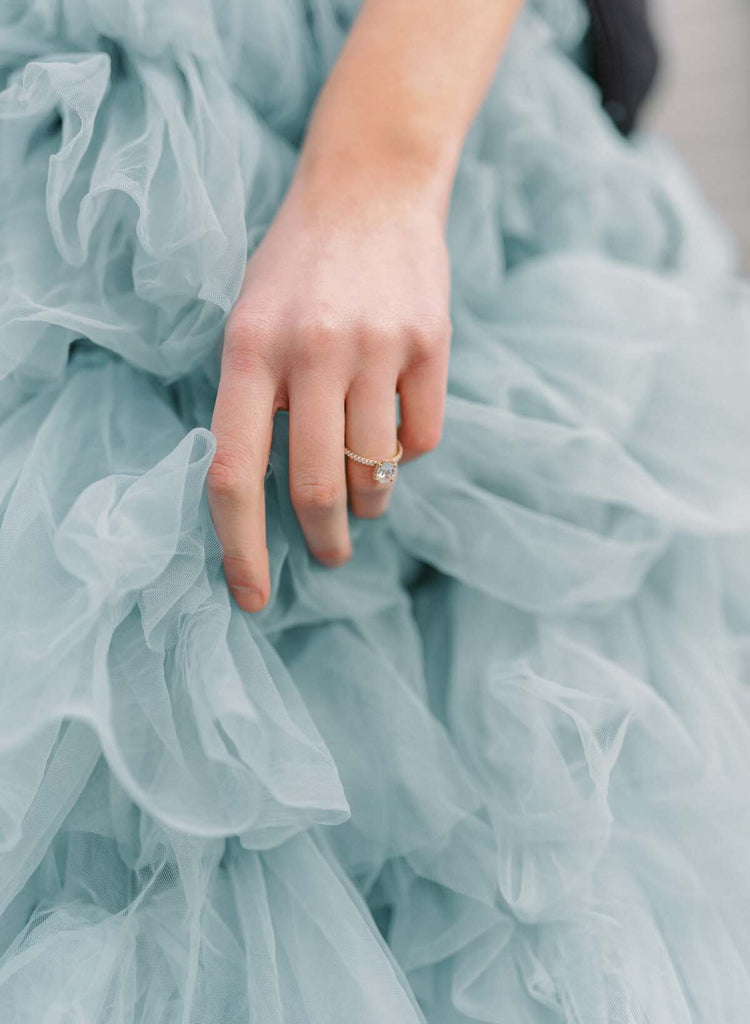Woman wearing engagement ring and blue ruffled dress