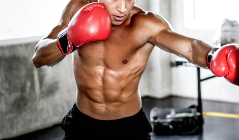 Shirtless man boxing wearing red boxing gloves