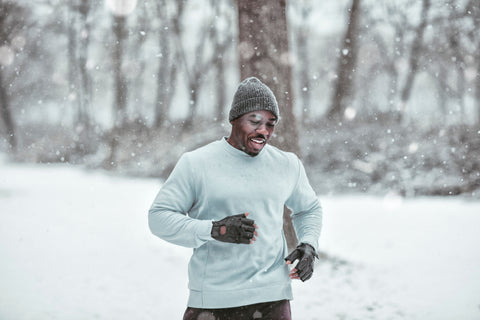 Handsome young black man running in a snowy landscape wearing a gray beanie