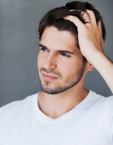 Handsome young man with clear, glowing skin running his hands through his strong, shiny hair