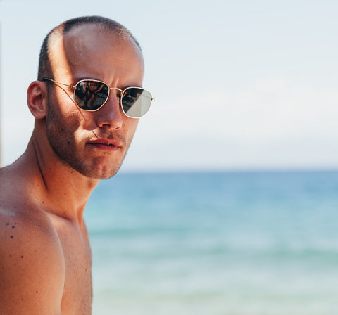 Handsome bald man wearing cool sunglasses by the sea
