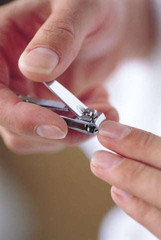 Man clipping his fingernails as part of manicure with stainless steel clippers