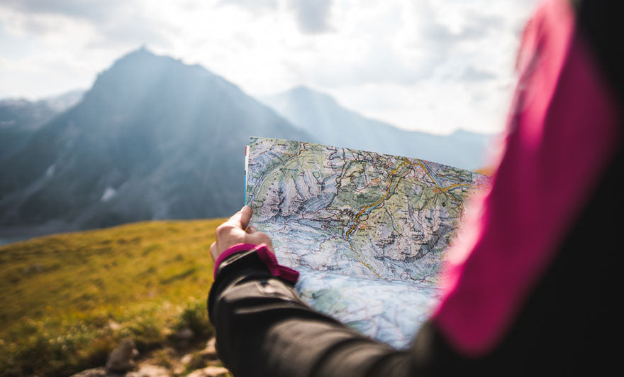 a person reviewing a map by a mountain range