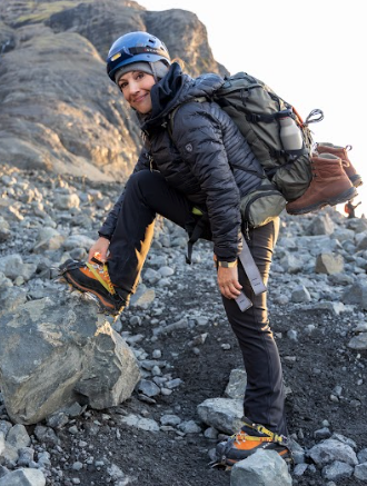 Royce stands on a boulder carrying backpack equiptment