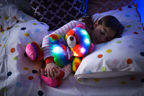 child sleeping with lighted bear