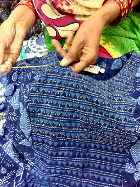 An artisan hand-stitching a fair trade dress.