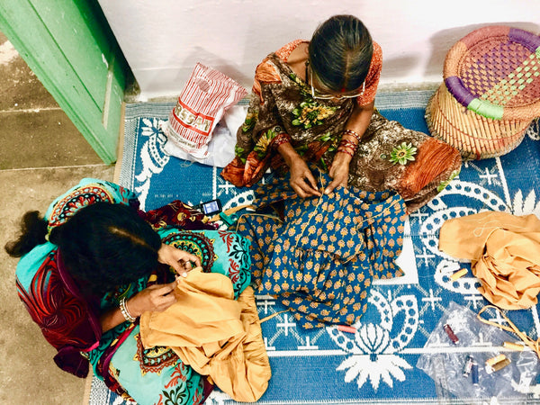 Artisans hand-stitching fair trade dresses.