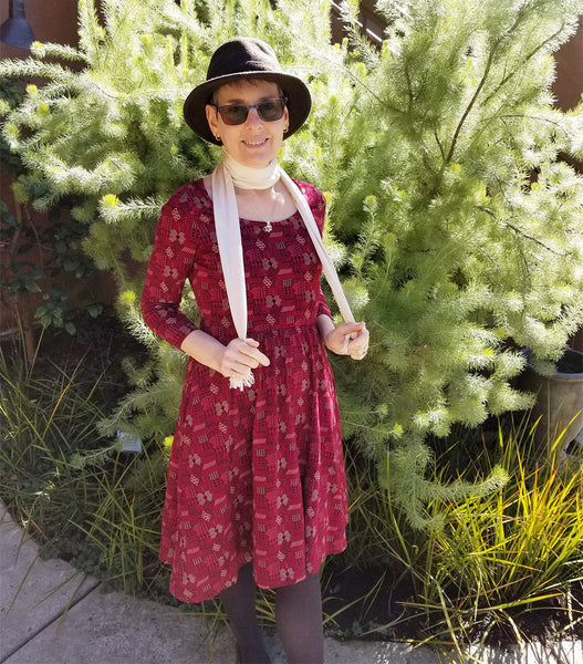 Deborah wearing a mid-length raspberry-colored printed Mata Traders dress with three-quarter sleeves, a fitted waistline, and a scoop neckline.
