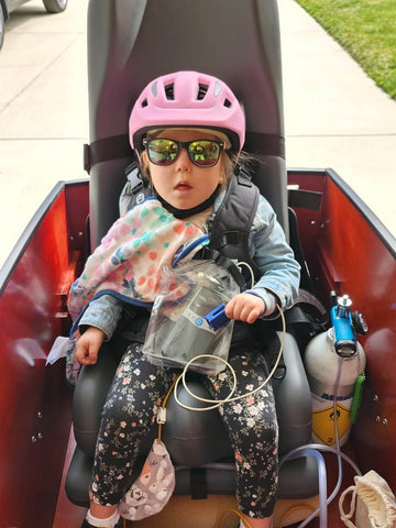 Child with medically complex needs in special tomato car seat in bunch bike