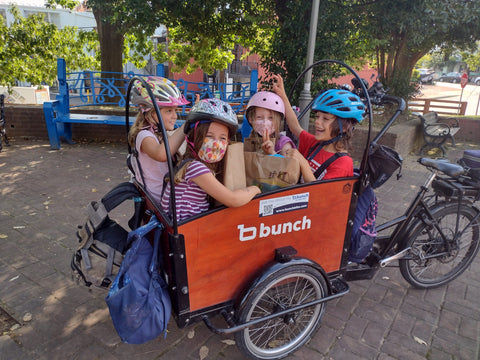 Four big kids in Bunch Bike with backpacks on outside