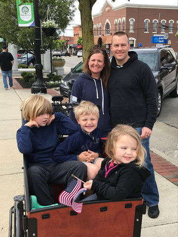 Three children, two with autism, riding in an adaptive trike with their parents. 