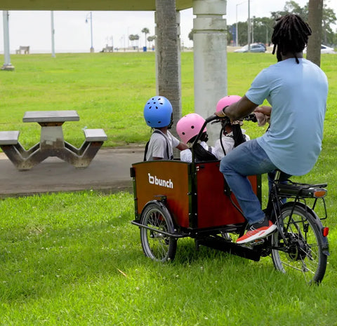 dad rides cargo bike with his family to picnic table