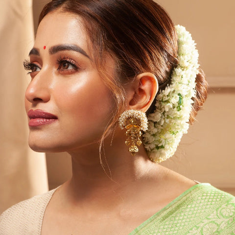 An image of a woman wearing a saree and a pair of Indian earrings.