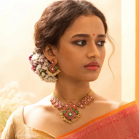An image of a woman wearing saree with an Indian necklace, crafted with meenakari stones.