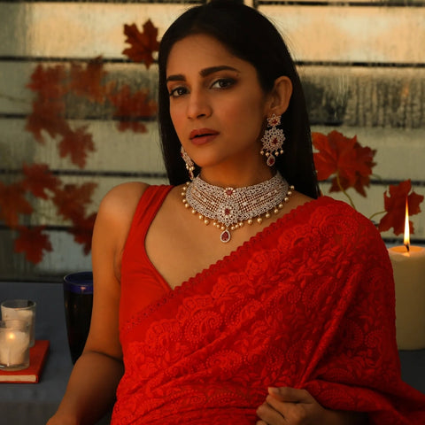 An image of a woman wearing red saree with stunning CZ choker set.