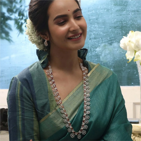 An image of a woman wearing an Indian long necklace, crafted with Cubic Zirconia and red gemstones