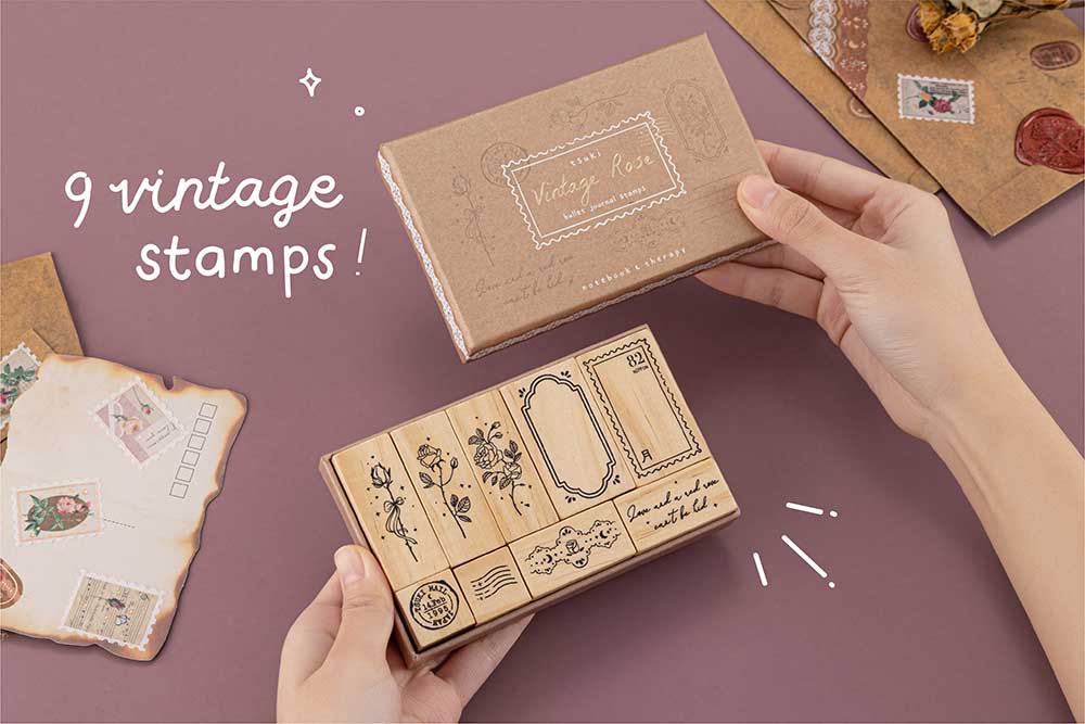 Tsuki ‘Vintage Rose’ Bullet Journal Stamp Set held in hands with dried roses and kraft paper letters and burnt paper on mauve background