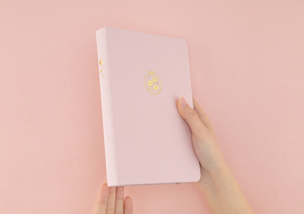 Hand holding Tsuki Sakura Breeze limited edition bullet journal by Notebook Therapy at an angle